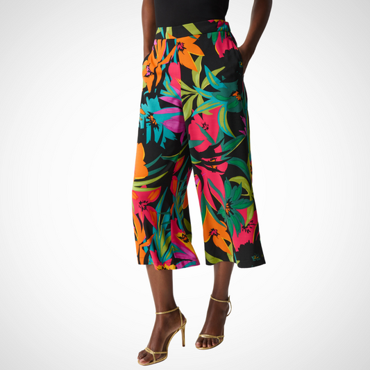 Jaboli Boutique - Fergus Ontario - Joseph Ribkoff - Tropical Print Palazzo Pant. Ease into these relaxed-fit, pull-on wide-legged pants from Joseph Ribkoff, featuring a vibrant multi-floral hibiscus print on a black background. The elegant, roomy crop design offers day-long comfort with the help of a stretchy waistband and the convenience of pockets. Perfectly paired with a coordinating top, this summery style is sure to become your new favorite. 